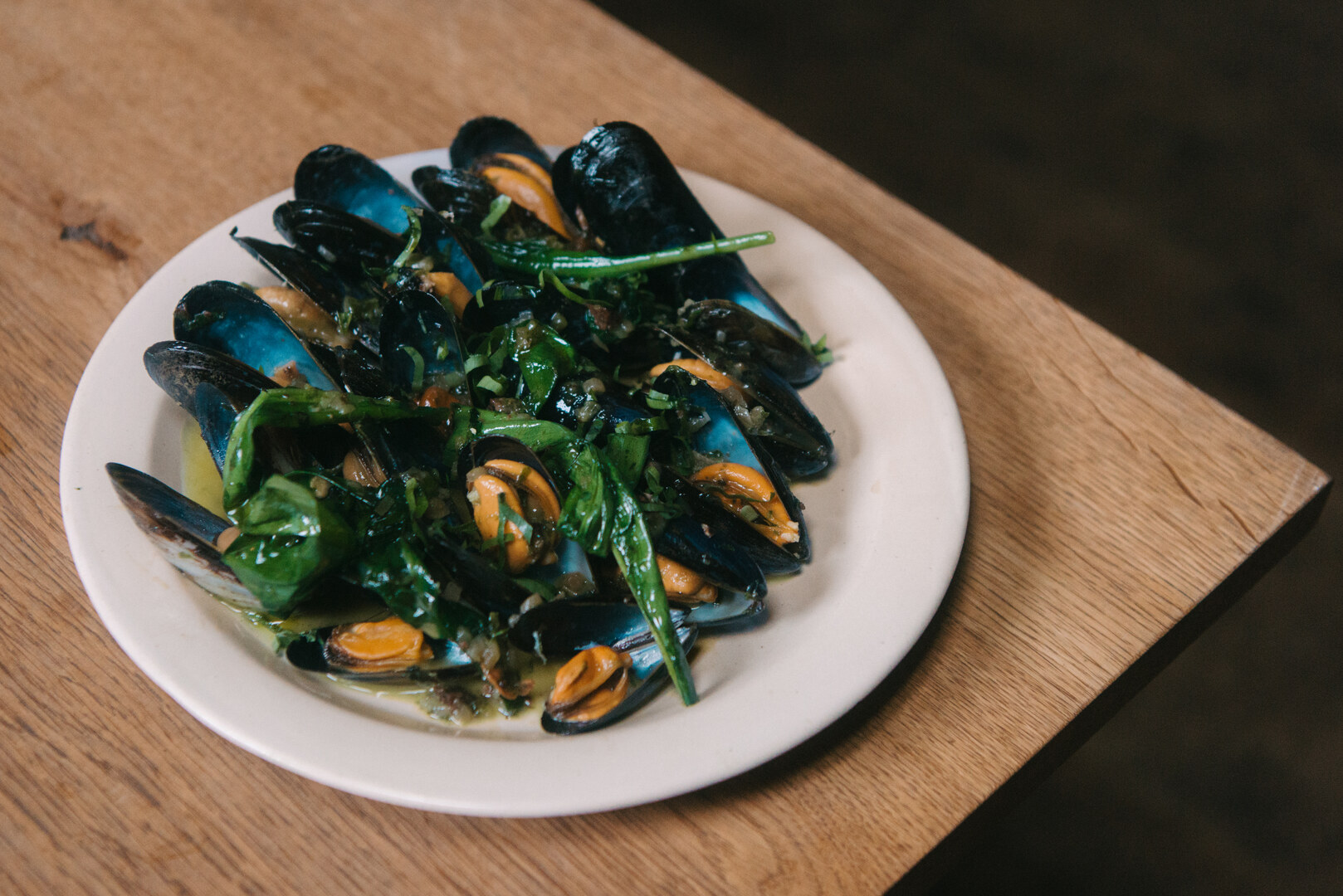 Mussels with greens on a white plate.