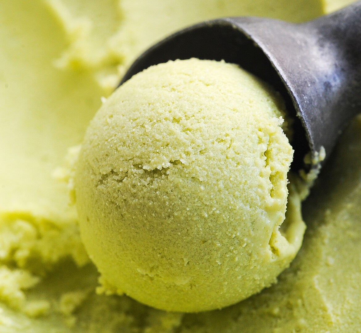 A scoop of light green ice cream on a scoop holder.