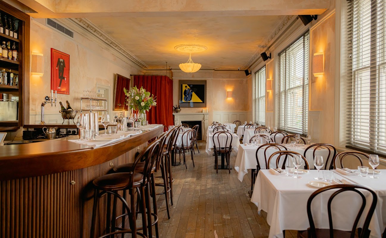 Interior of a restaurant with tables set for dining and a bar.