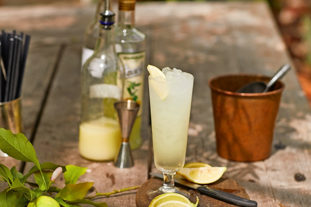Lemon cocktail on a wooden table with lemons and bar tools.
